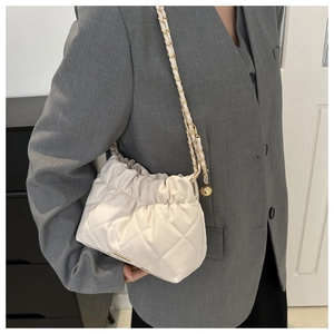 Detail of white quilted chain bag with gold adjustable ball buckle and textured leather