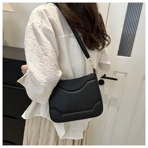 Dettaglio borsa a spalla in pelle nera opaca con cuciture curve e finiture dorate