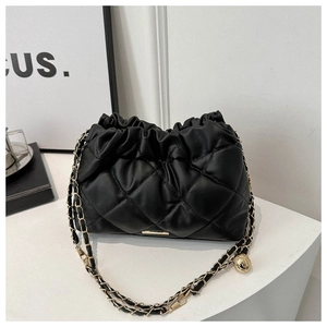 Close-up of black quilted cloud bag with gold chain strap and metal ball detail