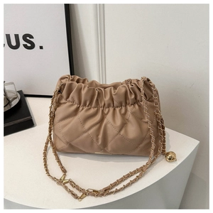 Close-up of beige quilted cloud bag with leather interwoven chain strap and metallic tag