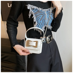 Detailed view of mini white crossbody bag with large silver bow buckle and chain strap