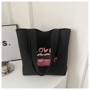 Dettaglio della stampa creativa labbra e LOVE su una borsa tote in tela nera capiente