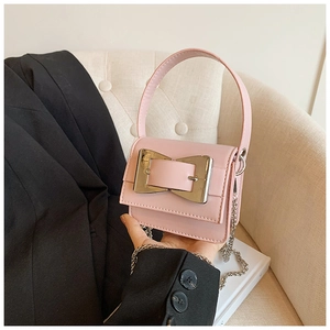Detailed macro view of pink mini faux leather handbag with oversized gold metal buckle