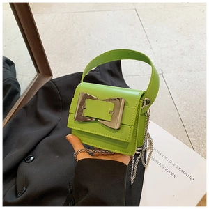 Detail of a bright green mini bag featuring a large silver buckle and metal chain strap