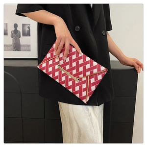 Détail de la pochette enveloppe tissée rouge et blanc avec garniture dorée portée