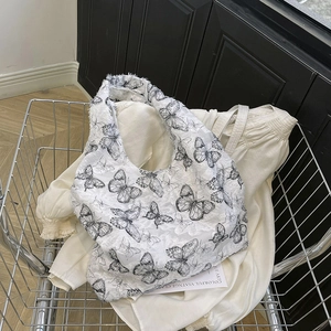 Detail of white canvas bag featuring black butterfly print and fringe edges in a basket