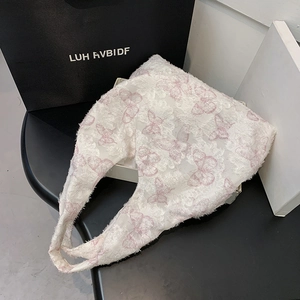 Detail of white lace tote bag featuring pink butterfly embroidery and fringe edges