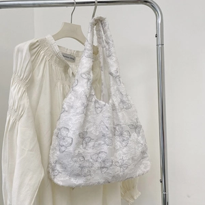 Close-up of white canvas tote bag featuring butterfly embroidery and fringe lace edges