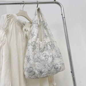 Detail of white lace tote bag with 3D butterfly embroidery on mesh fabric