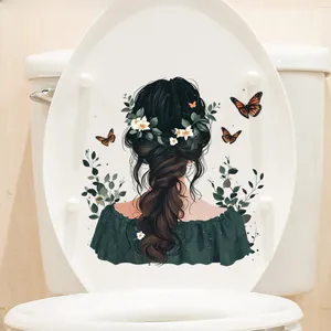 Close-up of cute girl angel sticker with green leaves on a white toilet cover lid