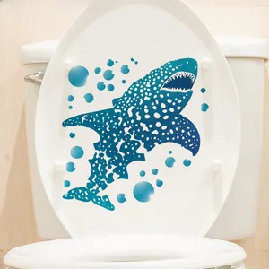 Close-up of a blue whale shark decal on a white toilet lid in a bathroom setting
