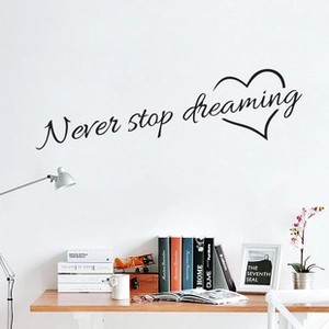 Sticker mural noir Never stop dreaming avec contour de coeur sur un bureau de chambre
