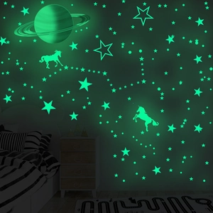 Luminous wall stickers featuring Saturn, unicorn, and stars glowing in a dark bedroom