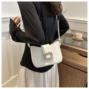 Macro detail of a white patent leather baguette bag with a square silver rhinestone buckle