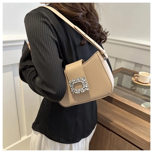 Close-up of elegant beige underarm bag featuring a luxury crystal buckle and faux leather