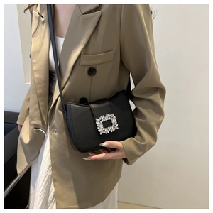Detail of black leather shoulder bag with sparkling crystal rectangle buckle decoration