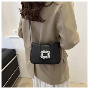Detail of a black flap bag featuring a luxury square rhinestone buckle on suit