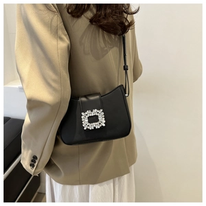 Detail of black leather underarm bag with sparkling rhinestone square buckle decoration