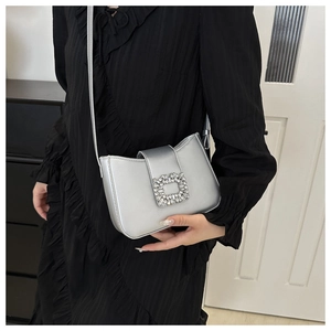 Detail view of a silver shoulder bag featuring a sparkling square rhinestone buckle