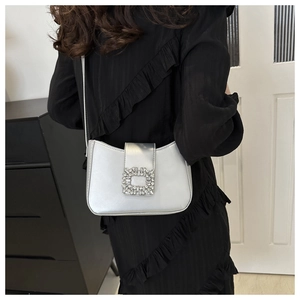Detail of silver faux leather underarm bag featuring a luxury square crystal buckle