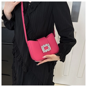 Model wearing a vibrant magenta leather shoulder bag with a square rhinestone buckle