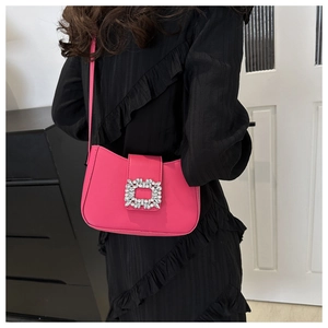 Detail of rose red shoulder bag with sparkling rectangular crystal buckle on dress