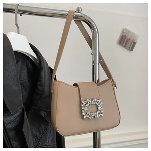 Detail of beige baguette bag featuring a luxury rhinestone buckle and smooth faux leather