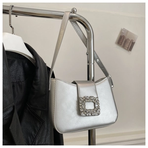 Detail of silver baguette bag featuring a large rectangular rhinestone buckle and metallic leather