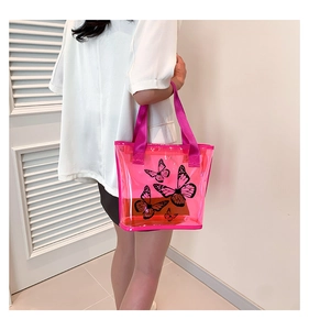 Pink transparent tote bag detail with butterfly print and woven handles on a shoulder view