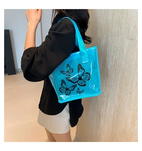 Detail of blue transparent tote bag featuring a black butterfly pattern and woven strap