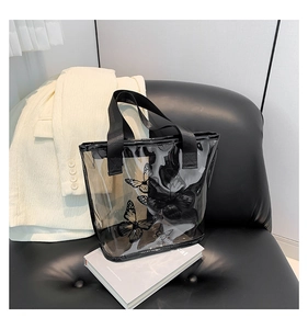 Detail of transparent PVC tote bag featuring black butterfly print and durable woven strap