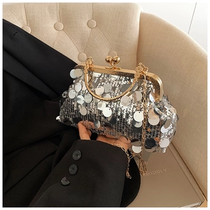 Detail of silver sequin evening bag with gold metal clasp and chain strap on blazer