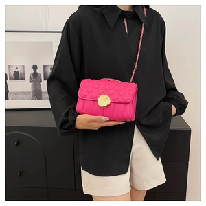Detail of fuchsia quilted mini bag with gold round buckle and chain strap shown on model