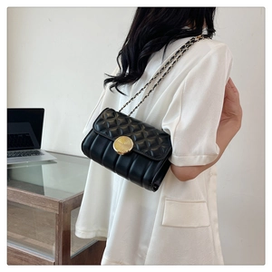 Detailed view of black quilted crossbody bag with gold round clasp and chain strap