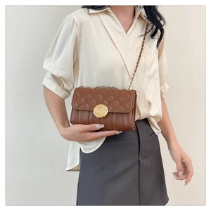 Detail of dark brown crossbody bag with quilted rhombic texture and gold clasp