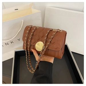 Detail of brown quilted bag featuring a round gold spiral lock and metal chain strap