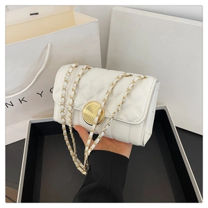 Detail of white quilted crossbody bag with golden spiral lock and metal chain strap