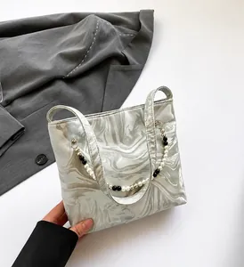 Detail of silver marble texture handbag with unique pearl and black beaded chain strap