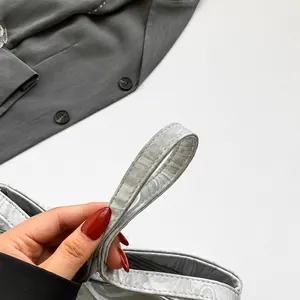 Detail of grey beaded handle and satin snake pattern texture on fashionable handbag