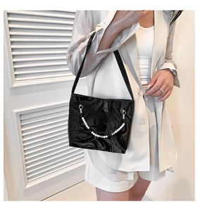 Detail of glossy black shoulder bag with stylish beaded chain and marble texture finish