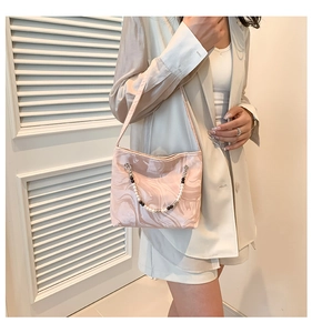 Detailed texture of pink marble pattern satin bag with decorative pearl chain strap