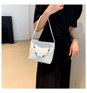 Detail of white minimalist underarm bag featuring a black and white pearl beaded chain