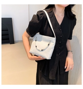 Close-up of white marble pattern handbag with decorative black and white beaded chain