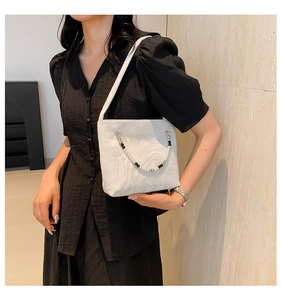 Detail of white marble textured handbag with decorative black and white pearl bead chain