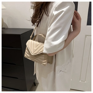 Detail van crème crossbodytas met V-stiksel, handvat en gepolijste afwerking