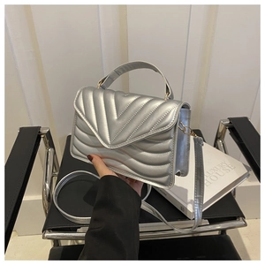 Detail van zilveren gewatteerde handtas met V-stiksels en metalen kettingriem