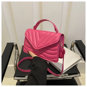 Detailopname van de roze gewatteerde crossbodytas met gouden hardware en V-patroon