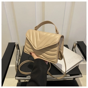 Detailopname van beige kunstleren handtas met V-vormig stiksel en fijne textuur