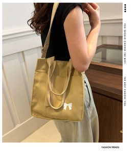 Close-up of khaki canvas tote bag with white bow print and adjustable shoulder strap