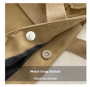 Detail view of the khaki canvas bag showing the magnetic hardware buckle closure